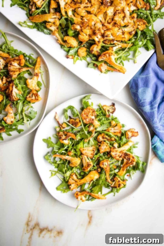 Green arugula on a plate, topped with golden roasted cauliflower