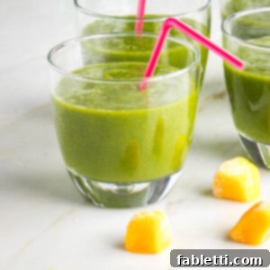 Small glass with bright green smoothie and pink straw.