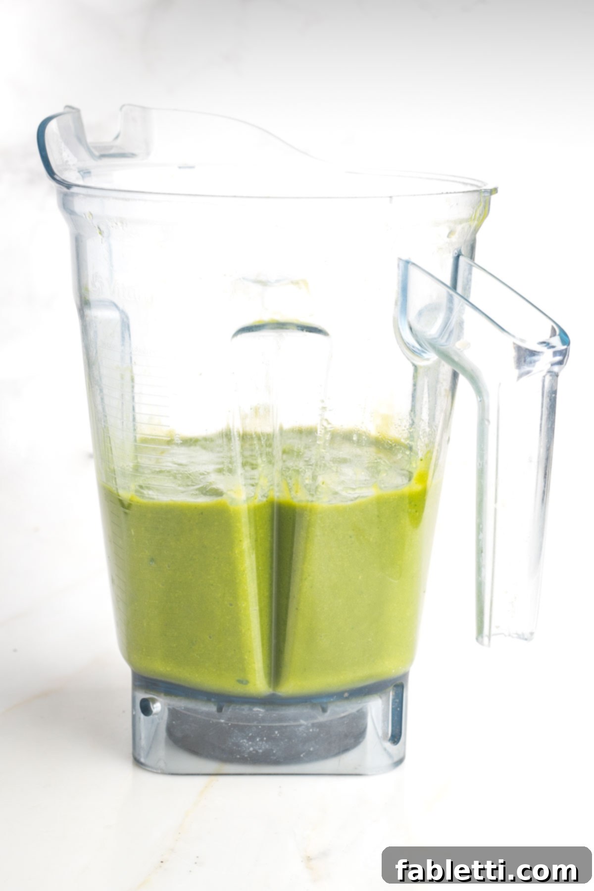 Blender in motion, creating a smooth green smoothie.
