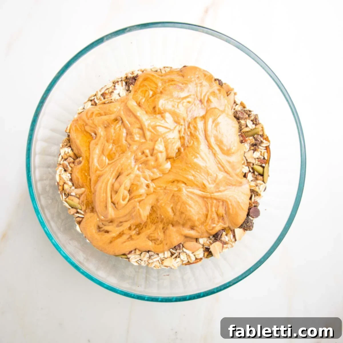 Golden Baked Granola Bites 11 Peanut butter and honey mixture poured on top of the oat mixture in a large bowl.