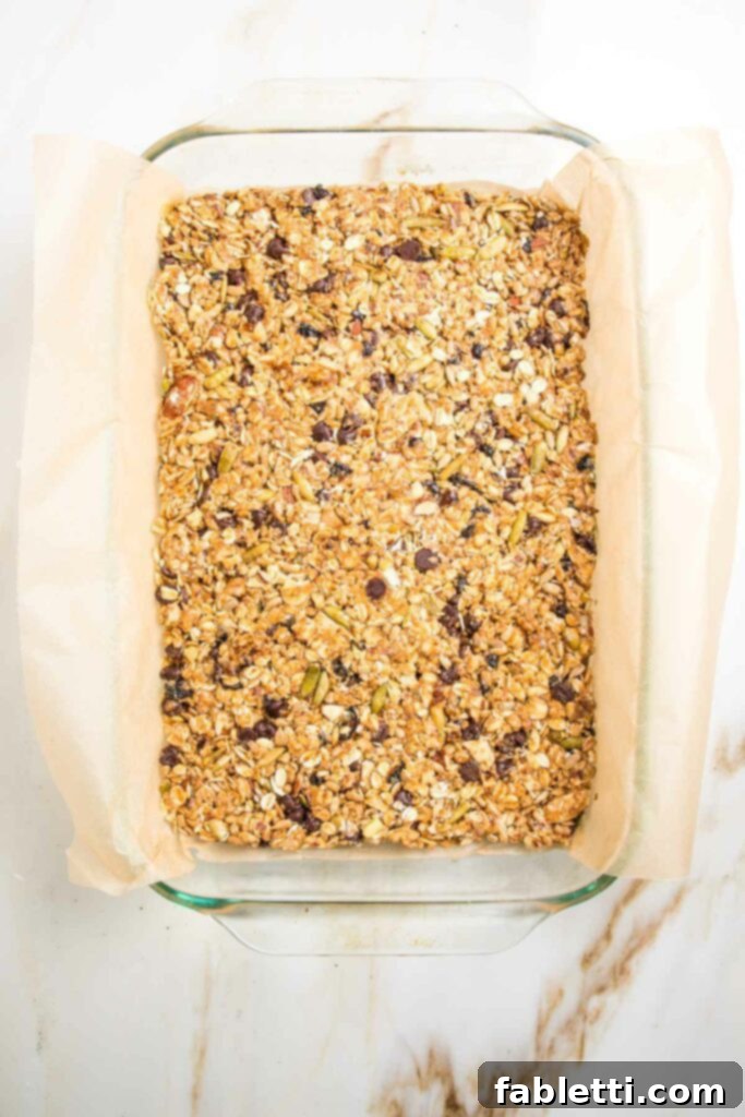 Golden Baked Granola Bites 15 Baked granola bars cooling in a glass dish lined with parchment.