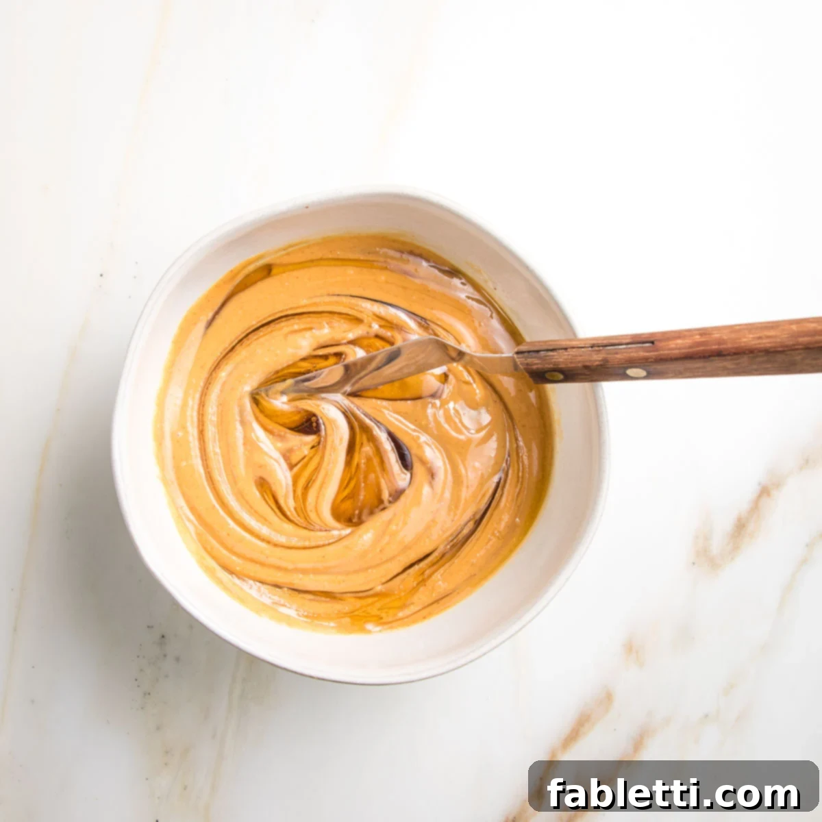 Golden Baked Granola Bites 10 Creamy peanut butter and honey swirled together in a small bowl, ready to be combined.