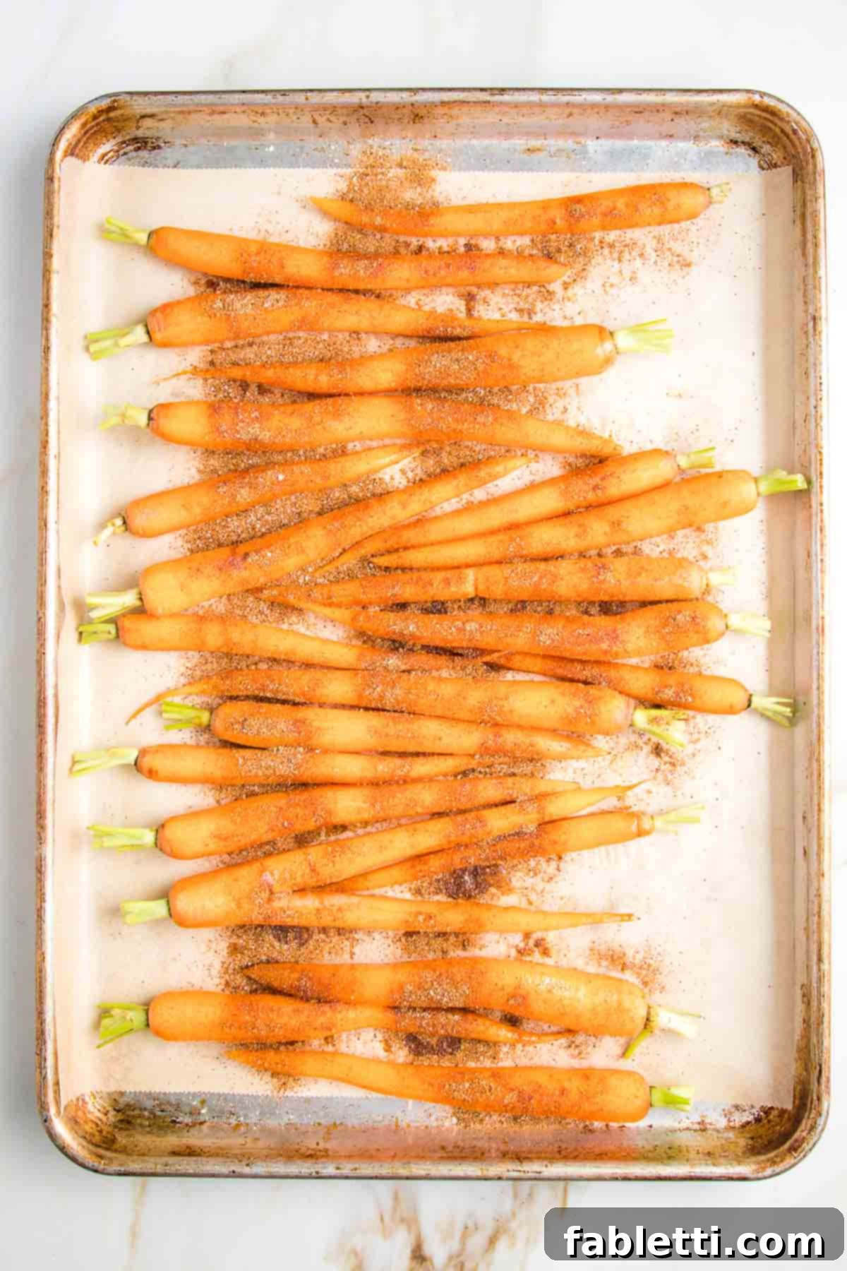 whole, trimmed carrots, drizzled with oil and sprinkled with spices on a parchment lined baking tray