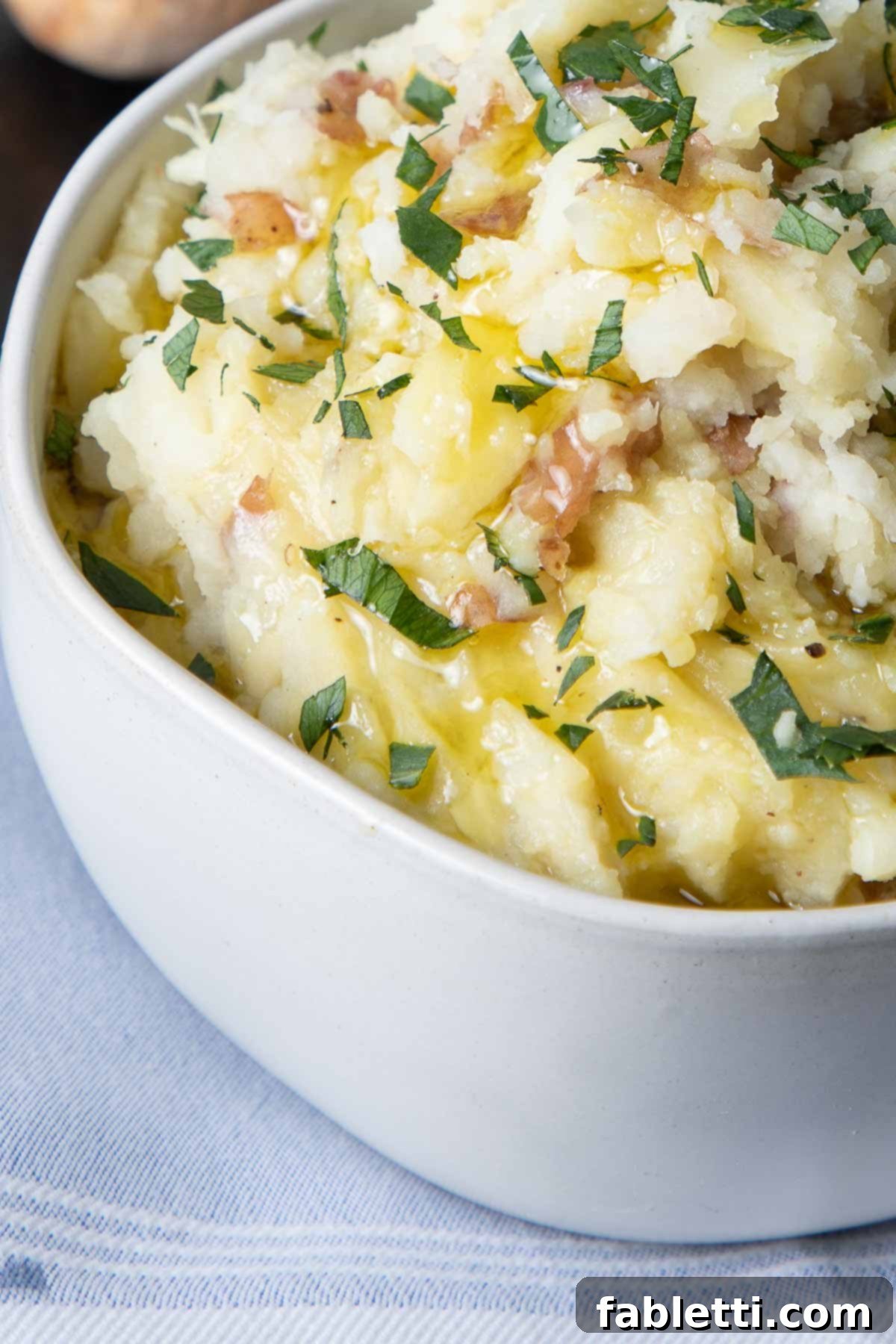 Heavenly Dairy-Free Garlic Mash 8 A close-up of a serving bowl filled with creamy mashed potatoes, generously garnished with freshly chopped parsley, ready to be served.
