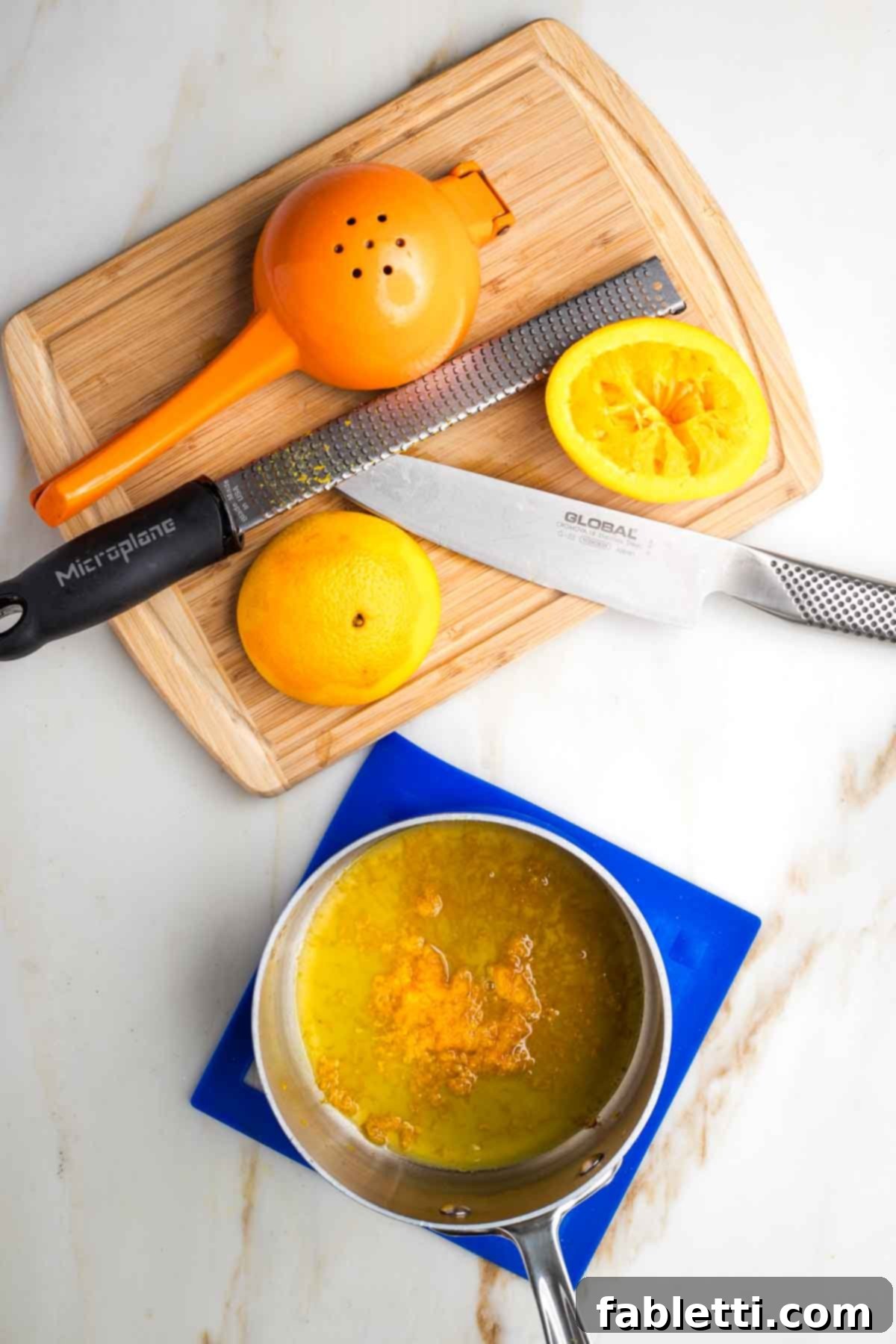 Refined Sugar-Free Cranberry Sauce 4 A small saucepan with vibrant orange zest and freshly squeezed orange juice. In the background, a microplane zester and the remains of the zested orange are visible, highlighting the fresh preparation.