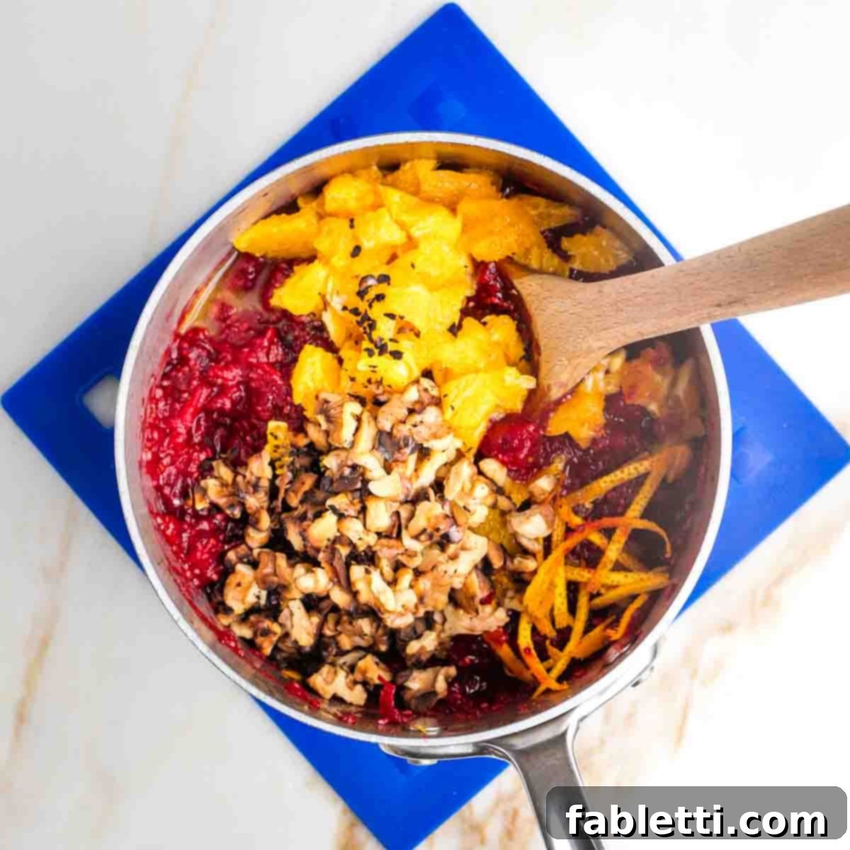Refined Sugar-Free Cranberry Sauce 10 A rich, red cranberry sauce in a small pot, now beautifully textured with chopped orange pieces, delicate orange zest, and crunchy toasted walnuts, creating a truly inviting and wholesome dish.