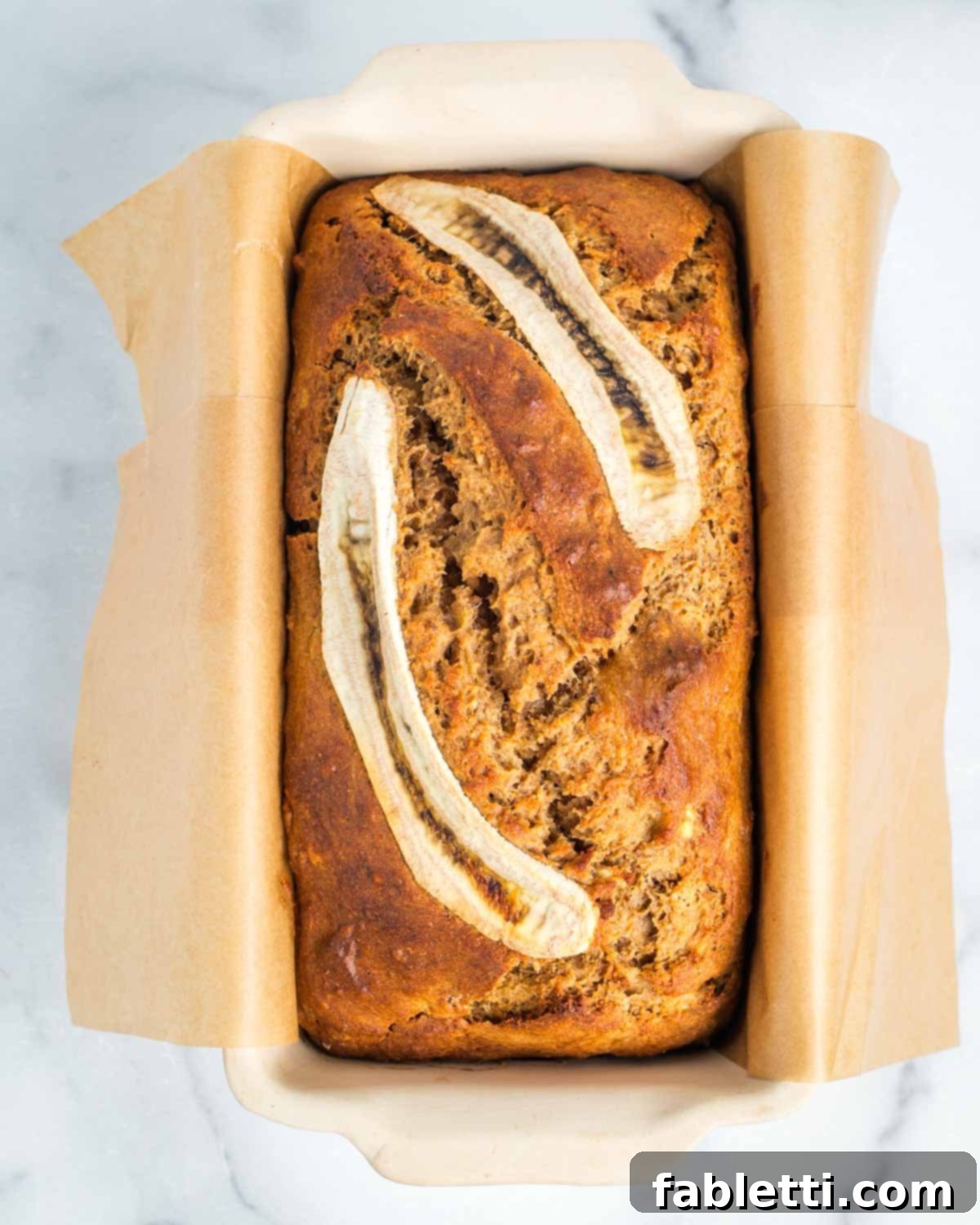 A freshly baked loaf of banana bread, golden and crisp on top, just removed from the oven.