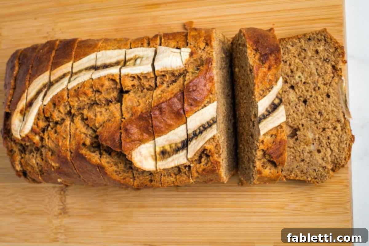 Thickly sliced banana bread with a decorative banana slice on top, ready to be served.