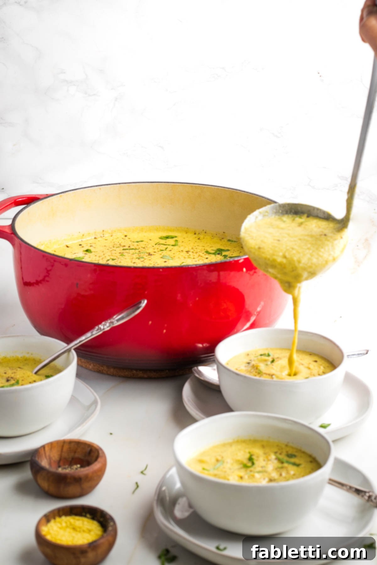 Velvety Plant-Based Broccoli Soup 15 Ladling creamy yellow soup into bowls.