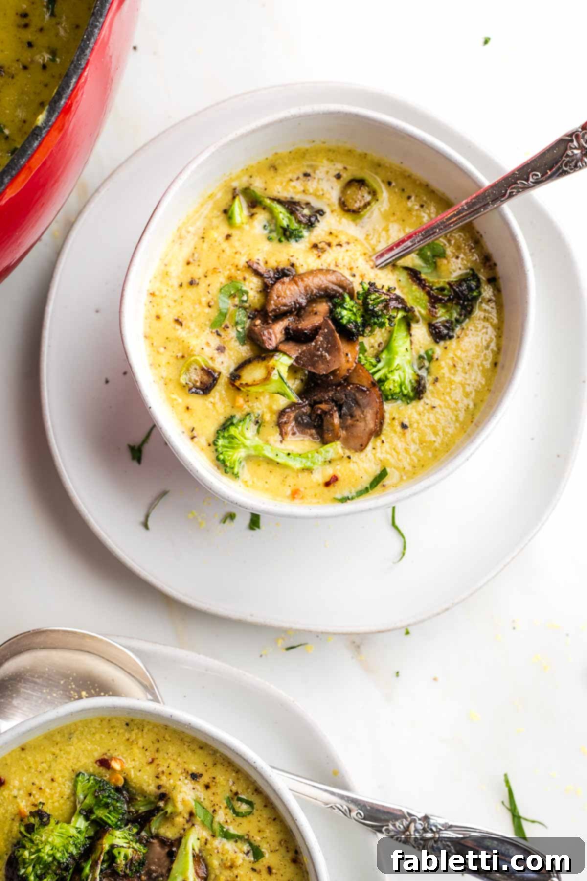Velvety Plant-Based Broccoli Soup 18 Bowls of creamy yellow soup with chunks of crispy broccoli and pepper floating on the surface, ready to be enjoyed.