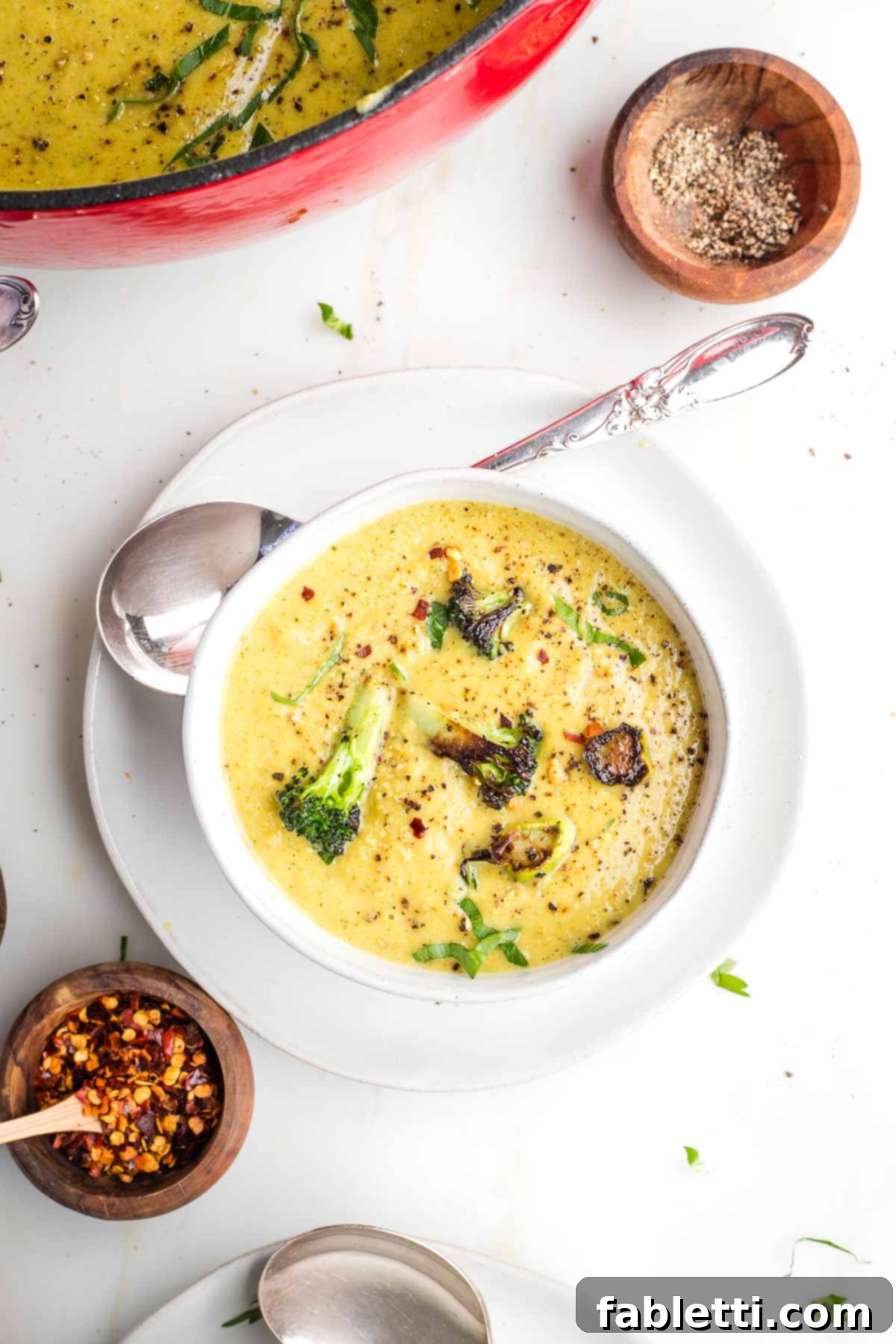 Velvety Plant-Based Broccoli Soup 19 Creamy yellow soup with crispy broccoli florets floating on top.
