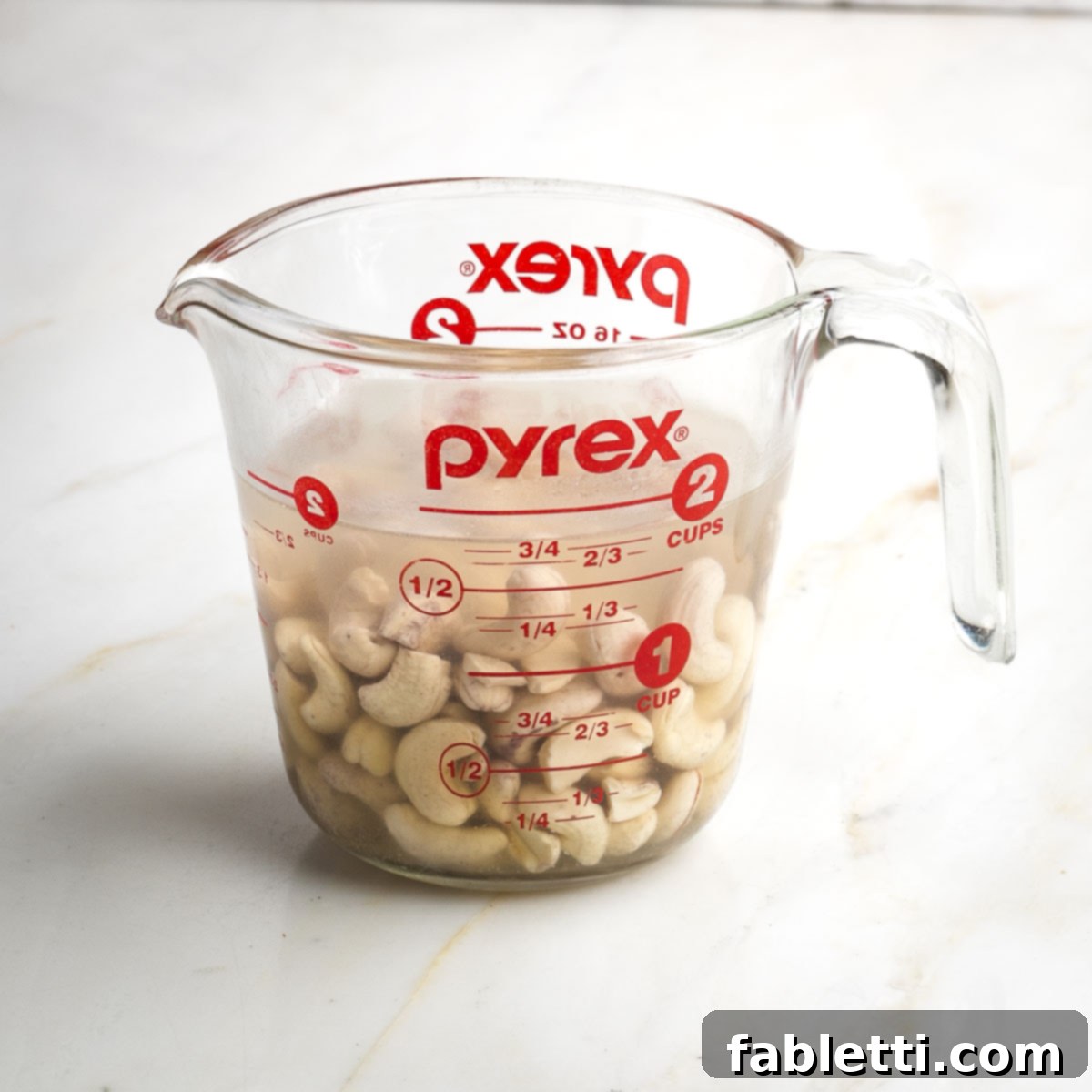 Velvety Plant-Based Broccoli Soup 4 Pyrex measuring cup with cashews immersed in water.