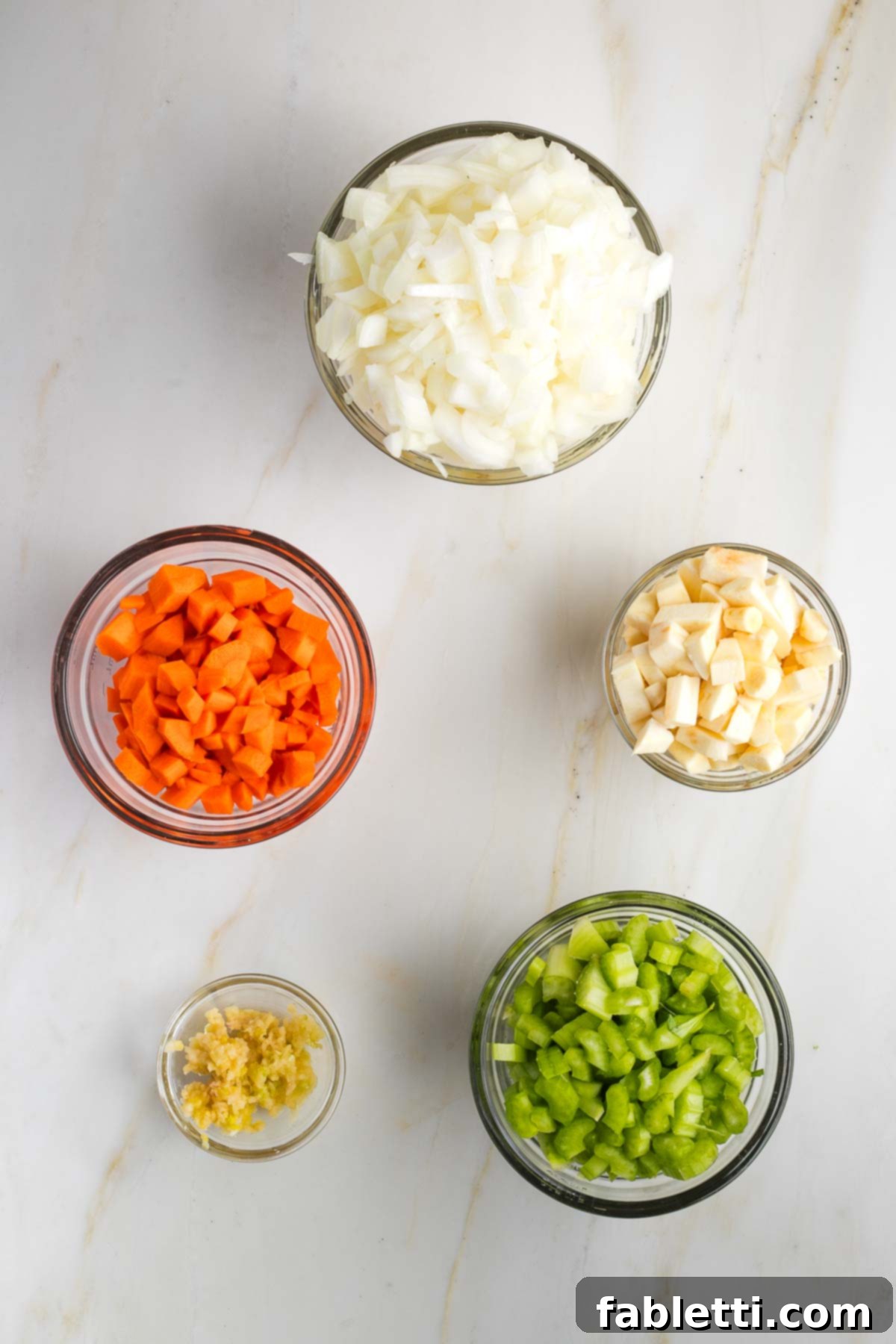Velvety Plant-Based Broccoli Soup 5 Prep bowls with diced onion, carrot, celery, parsnip and grated garlic.