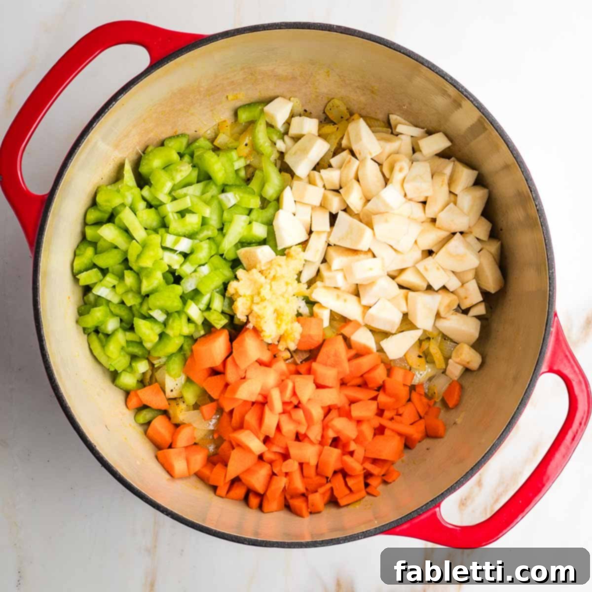 Velvety Plant-Based Broccoli Soup 8 Dutch oven with piles of chopped carrot, parsnip, celery and a heap of grated garlic.