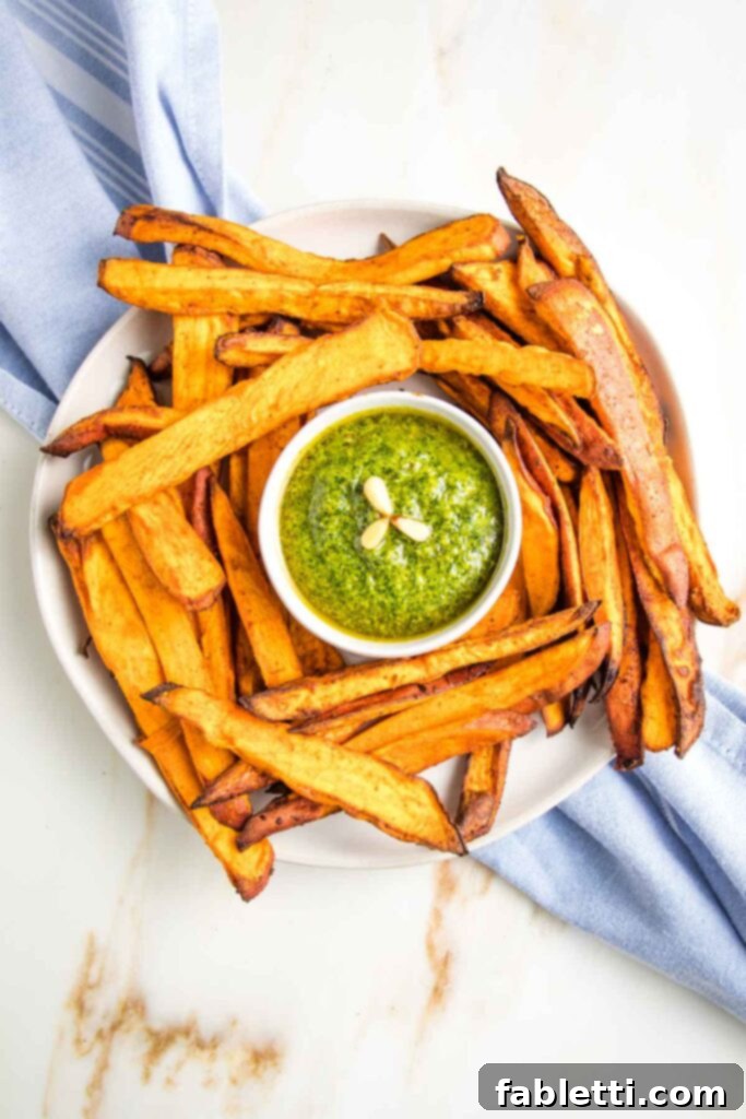 Golden Crispy Sweet Potato Fries 12 Large plate of crispy sweet potato fries with a small dish of bright green pesto in the center.