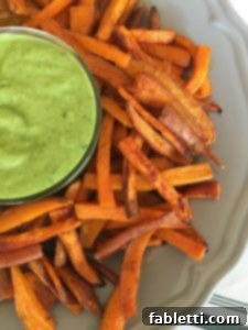 Golden Crispy Sweet Potato Fries 13 Crispy sweet potato fries on a grey plate with a dish of avocado dressing in the center.