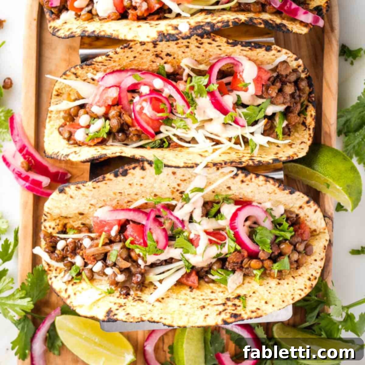 Hearty Vegan Lentil Tacos 10 Taco shells filled with lentils, pickled red onion, cabbage and hot sauce, ready to be served.