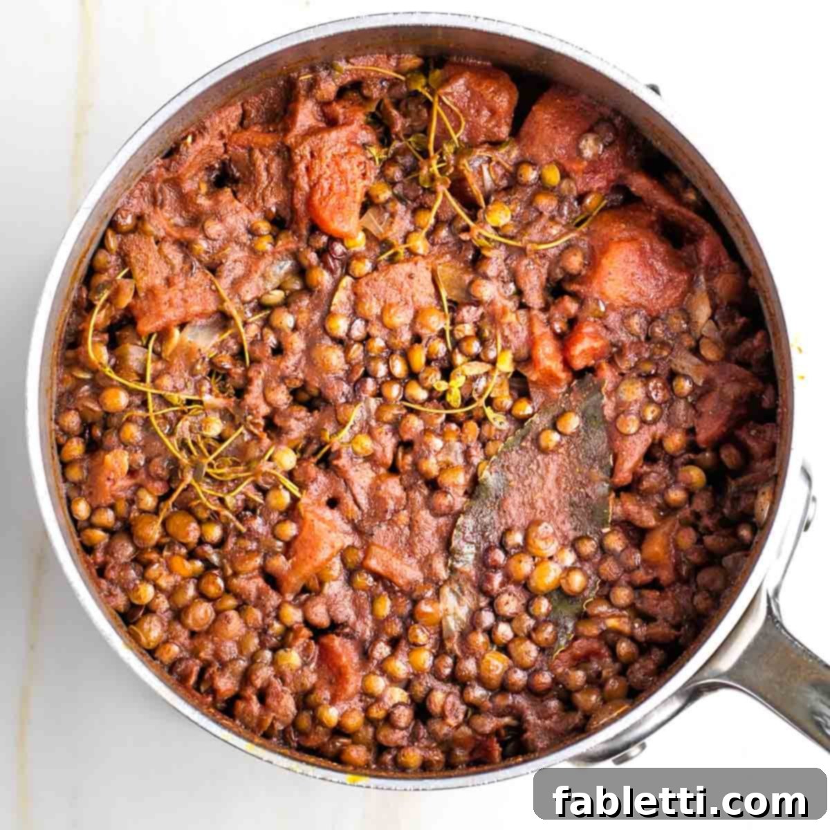 Hearty Vegan Lentil Tacos 9 Cooked lentil filling being fluffed with a fork after removing herbs.