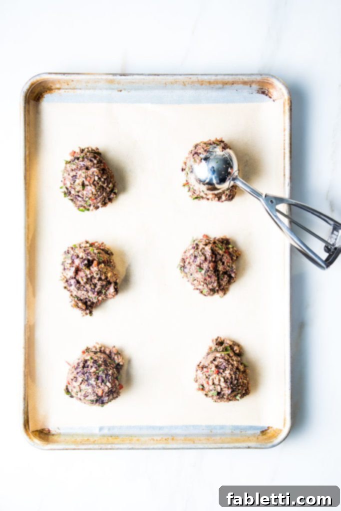 Plant-Powered Black Bean Burgers 8 Scoops of black bean veggie burger mixture carefully placed onto a baking tray lined with parchment paper, ready for shaping.