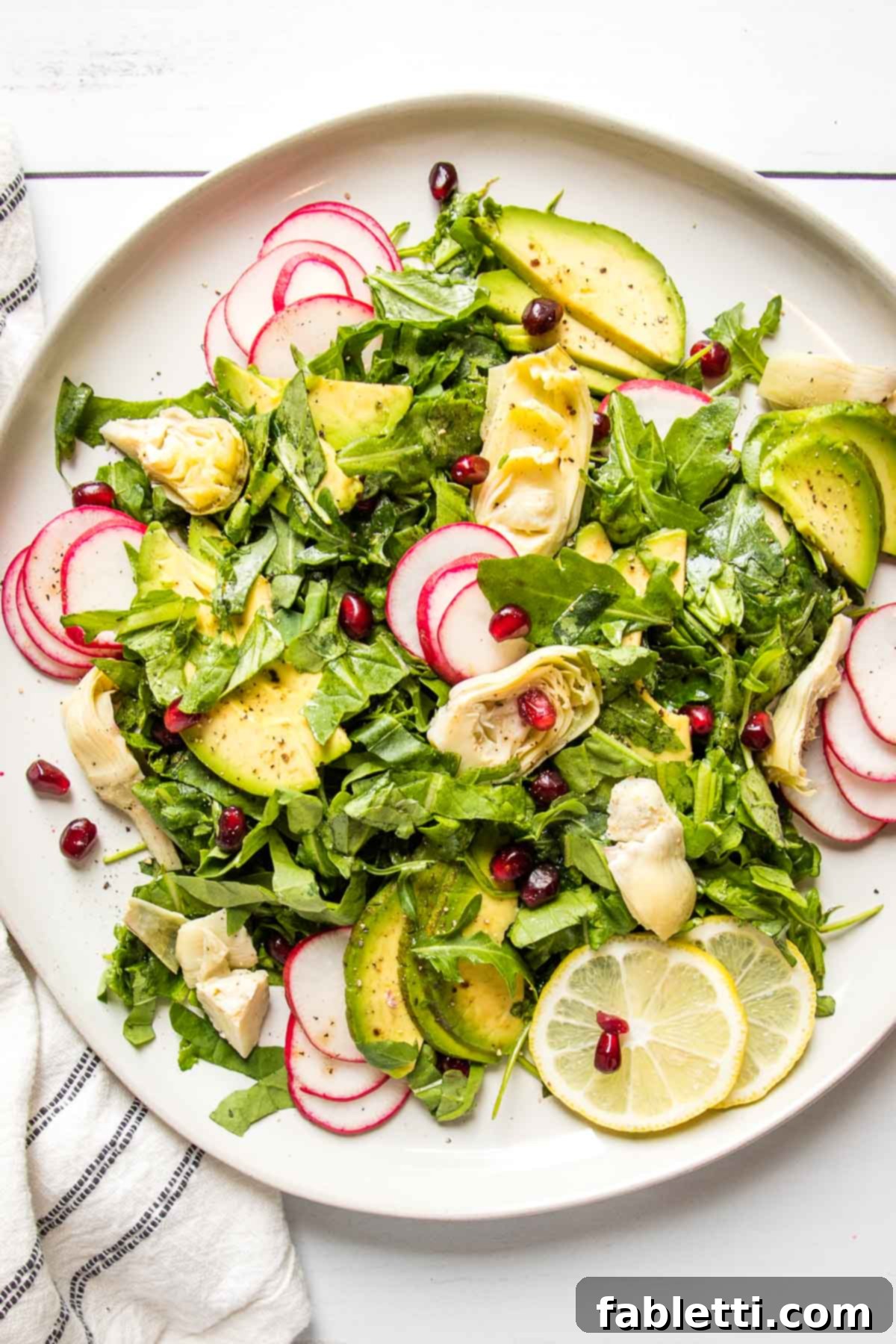 Vibrant Arugula & Lemon Salad 2 Arugula salad with vibrant green artichoke hearts, creamy avocado slices, thin radish slivers, and bright lemon slices arranged artfully in a bowl.