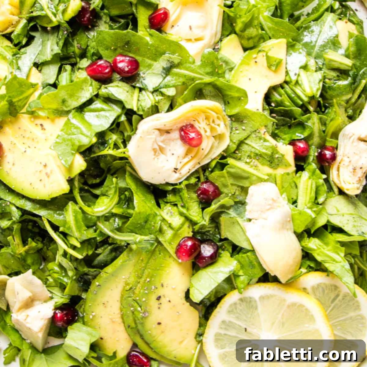 Vibrant Arugula & Lemon Salad 12 A close-up shot of the arugula salad, showcasing the texture of the greens, the creamy avocado, the tender artichoke hearts, and the sparkling pomegranate seeds, with a hint of lemon.