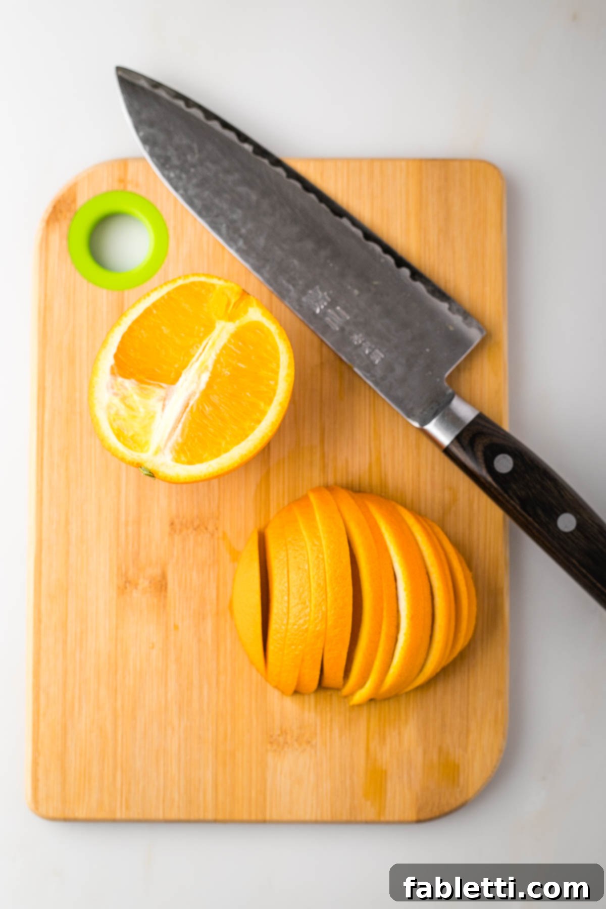 Nectar-Kissed Roasted Roots 5 An orange halved, with one side sliced into thin half moons on a cutting board.