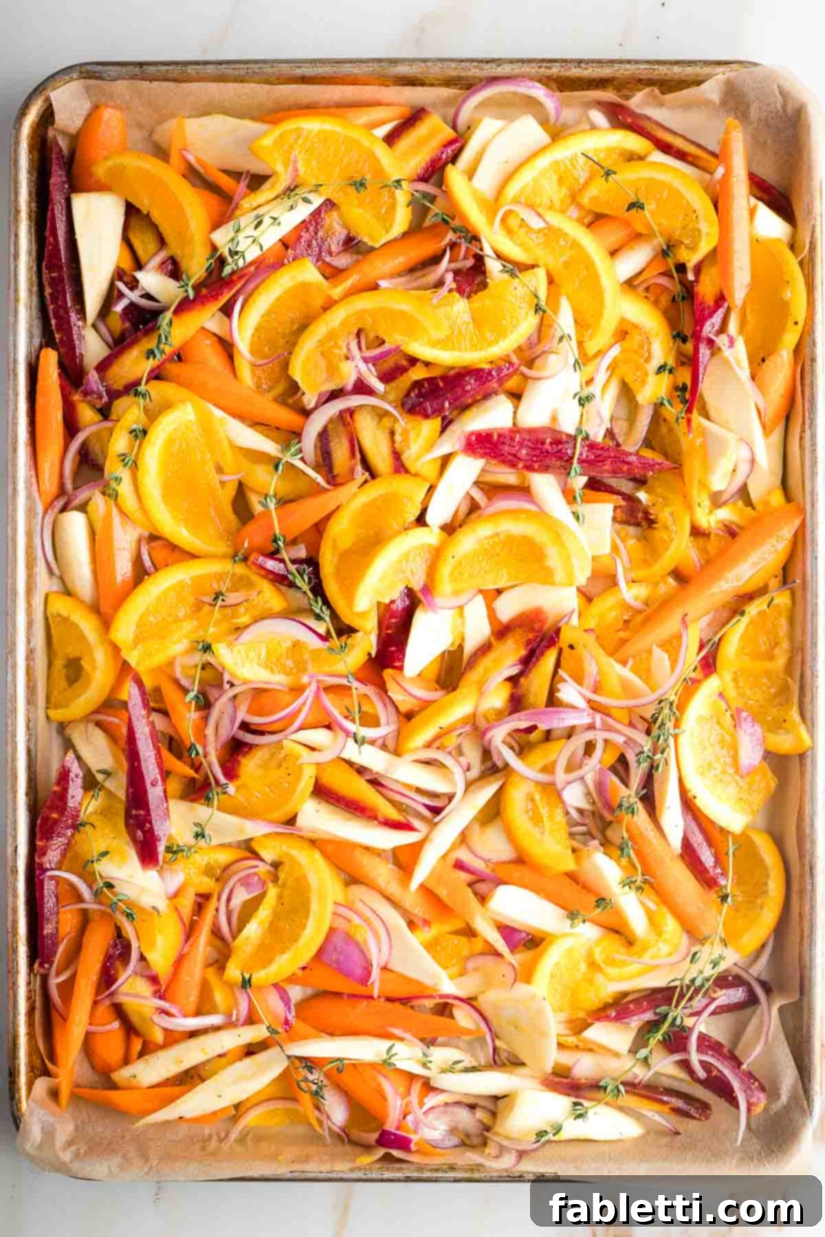 Nectar-Kissed Roasted Roots 8 Parsnips, carrots, oranges and onions in a honey glaze spread on a parchment-lined baking tray.