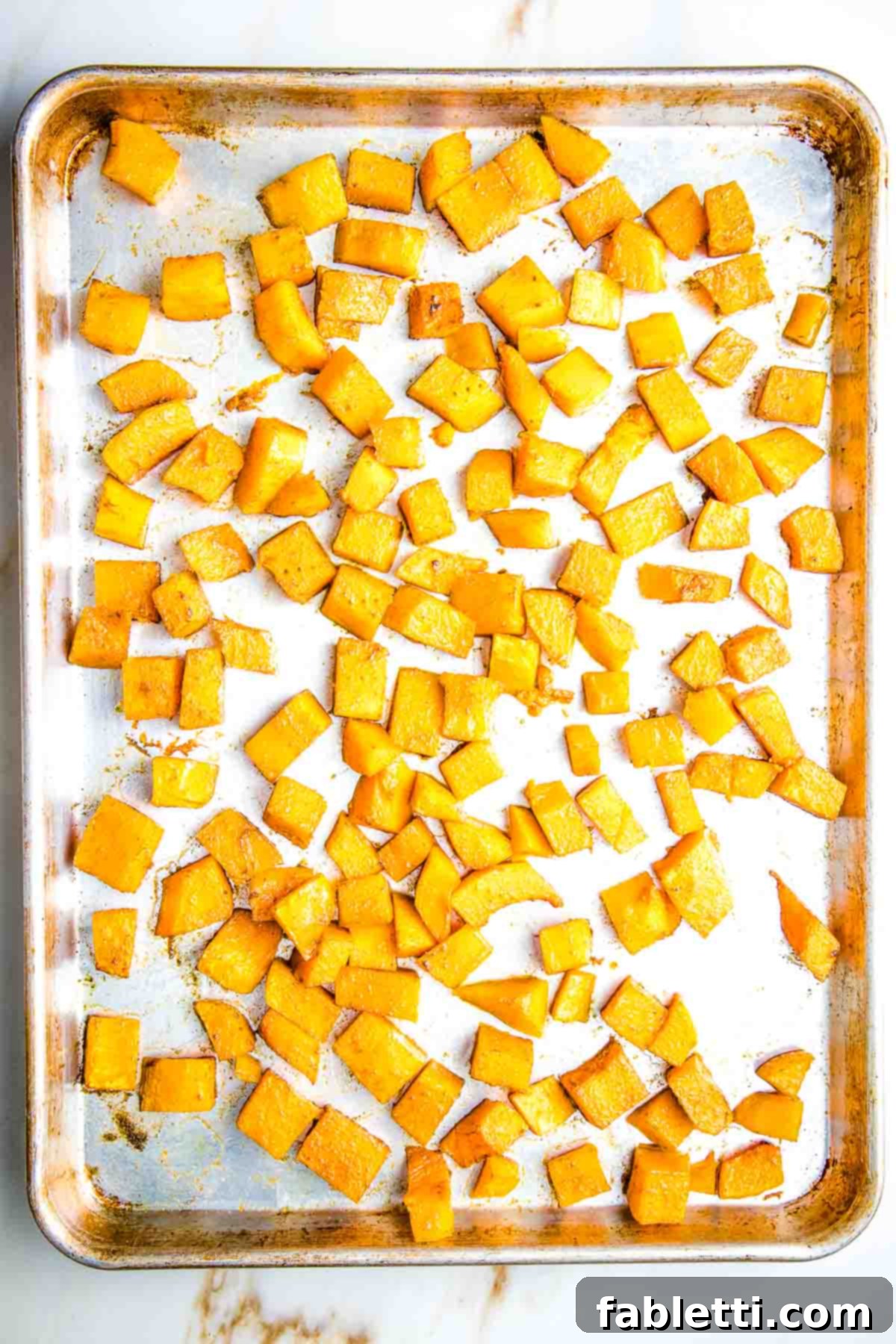 Vibrant Butternut Beetroot Medley 11 Roasted butternut squash cubes on a large rimmed baking sheet.