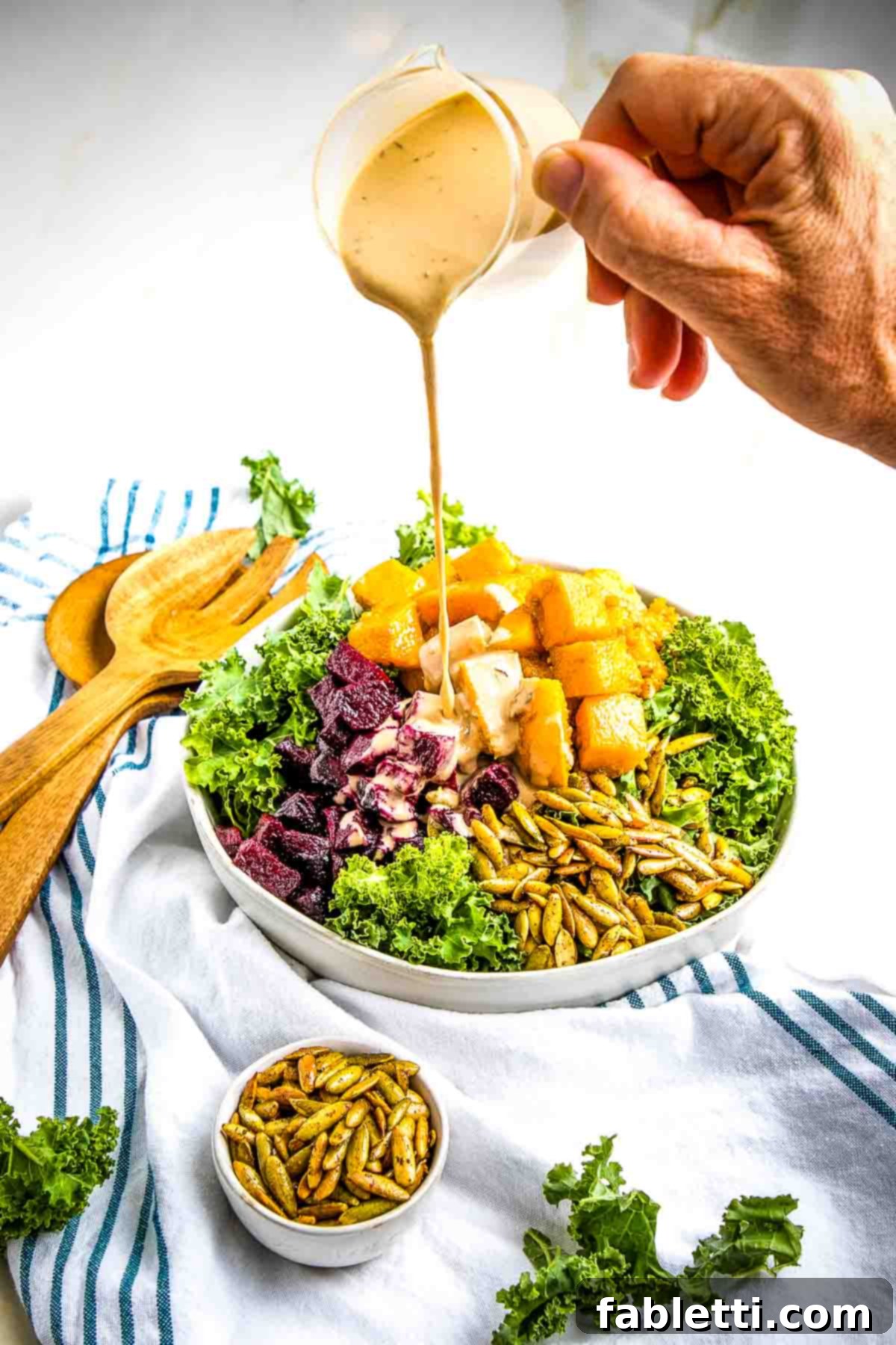 Vibrant Butternut Beetroot Medley 13 Pouring creamy dressing on top of roasted Butternut Squash and Beetroot cubes with kale.