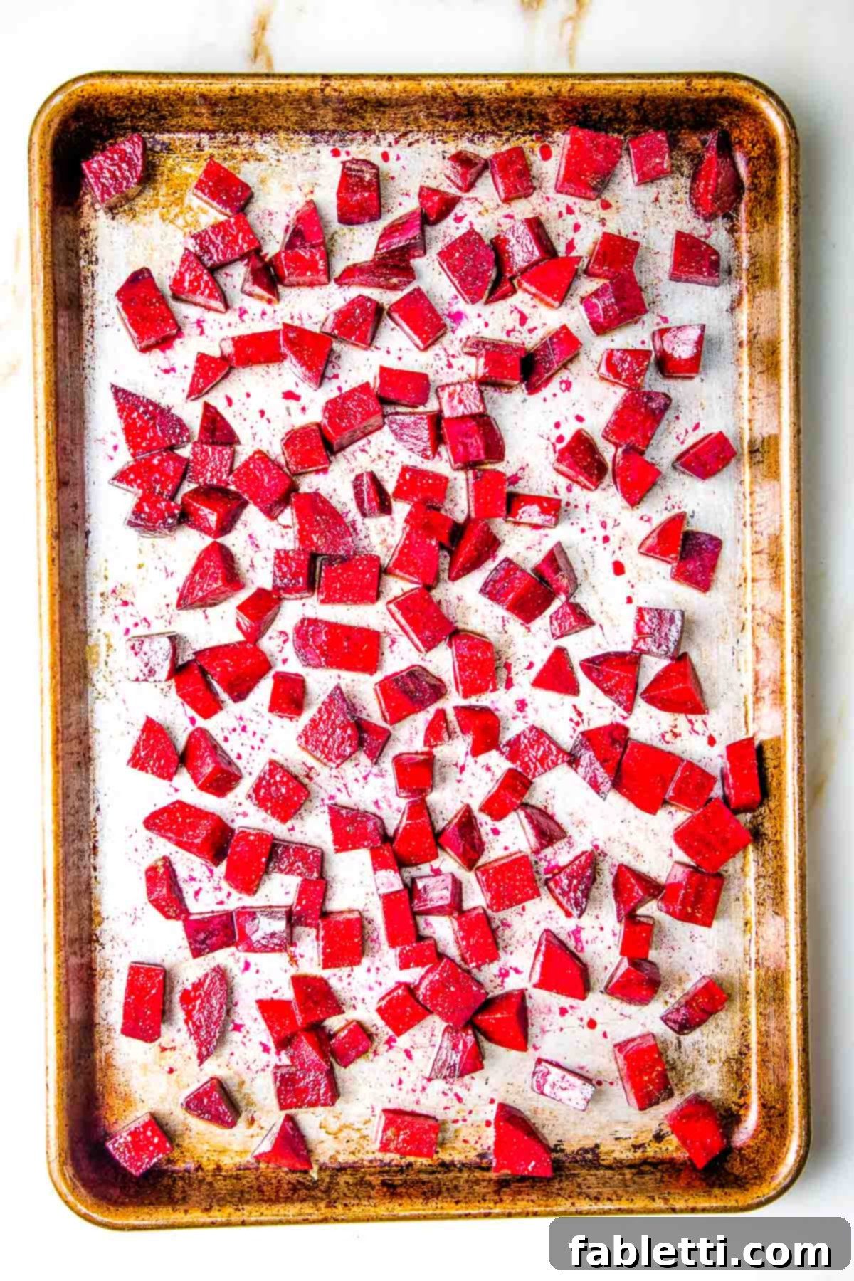 Vibrant Butternut Beetroot Medley 10 Small cubes of red beetroot on a rimmed baking sheet.