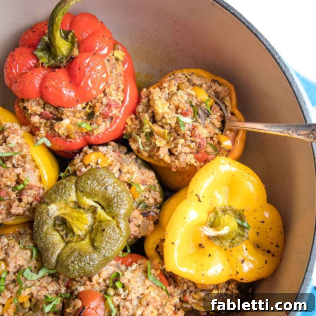 Hearty Vegan Lentil Stuffed Peppers 13 A selection of vibrant green, yellow, orange, and red vegan stuffed peppers, overflowing with quinoa, lentils, and Italian spices, nestled in a Dutch oven.