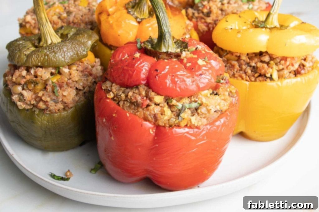 Hearty Vegan Lentil Stuffed Peppers 14 A close-up of vibrant vegan stuffed peppers in green, yellow, orange, and red, generously filled with a rich mixture of quinoa, lentils, and Italian spices.