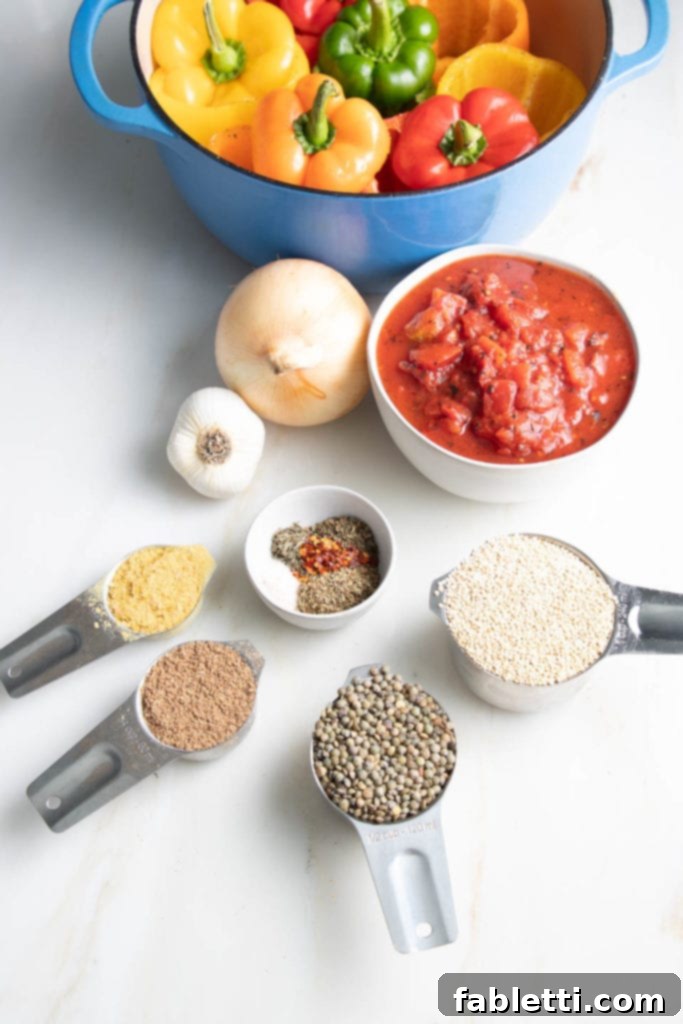 Hearty Vegan Lentil Stuffed Peppers 4 Ingredients for vegan stuffed peppers laid out: colorful bell peppers, diced tomatoes, quinoa, lentils, onions, garlic, Italian spices, ground flax, and nutritional yeast.