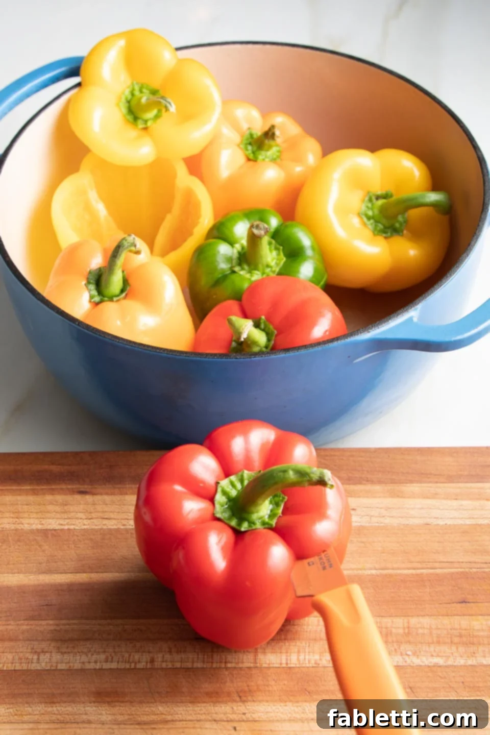 Hearty Vegan Lentil Stuffed Peppers 5 A sharp knife cutting a quarter-inch off the top of a bell pepper.
