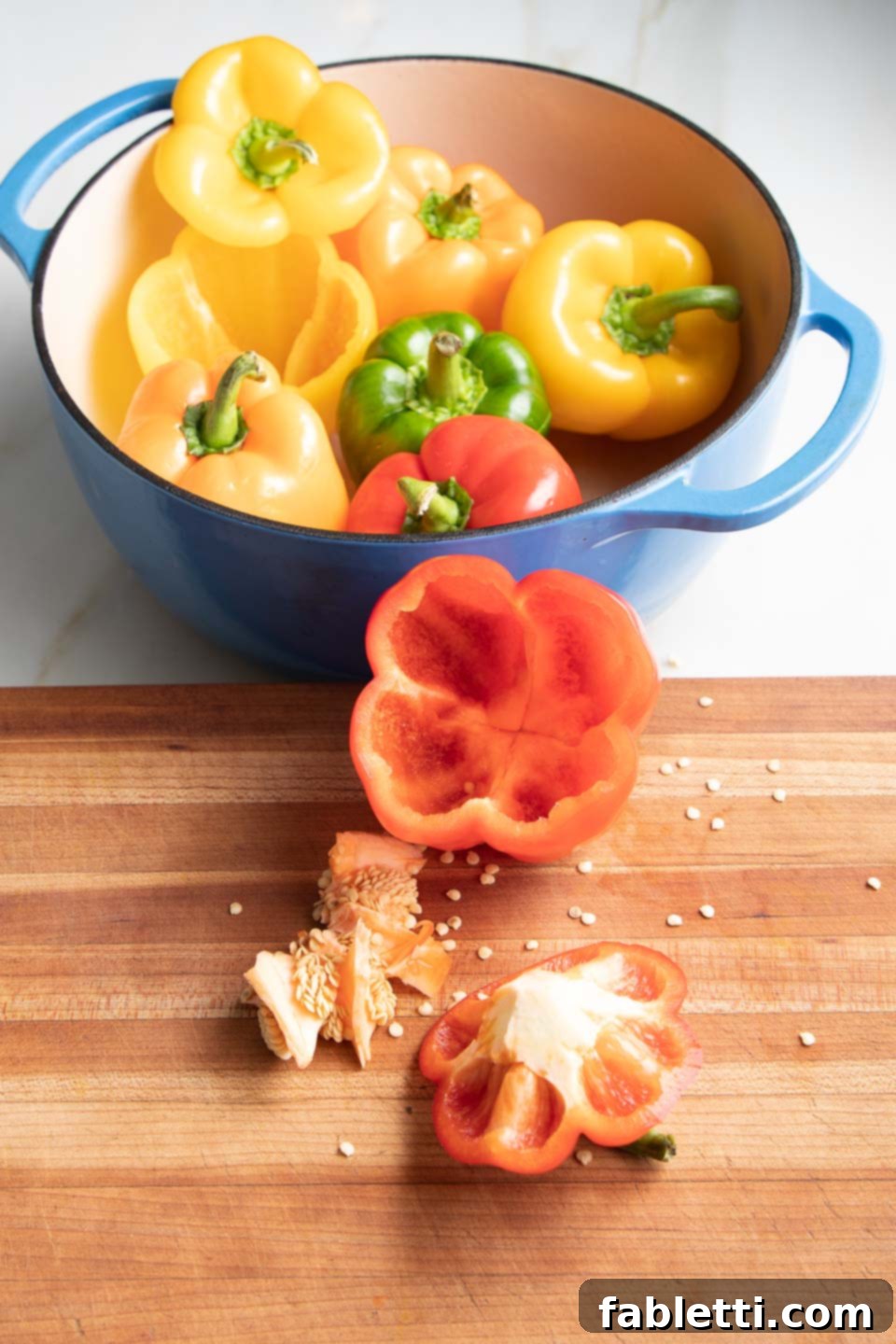 Hearty Vegan Lentil Stuffed Peppers 6 Hands scooping out the core, membranes, and seeds from inside a bell pepper.