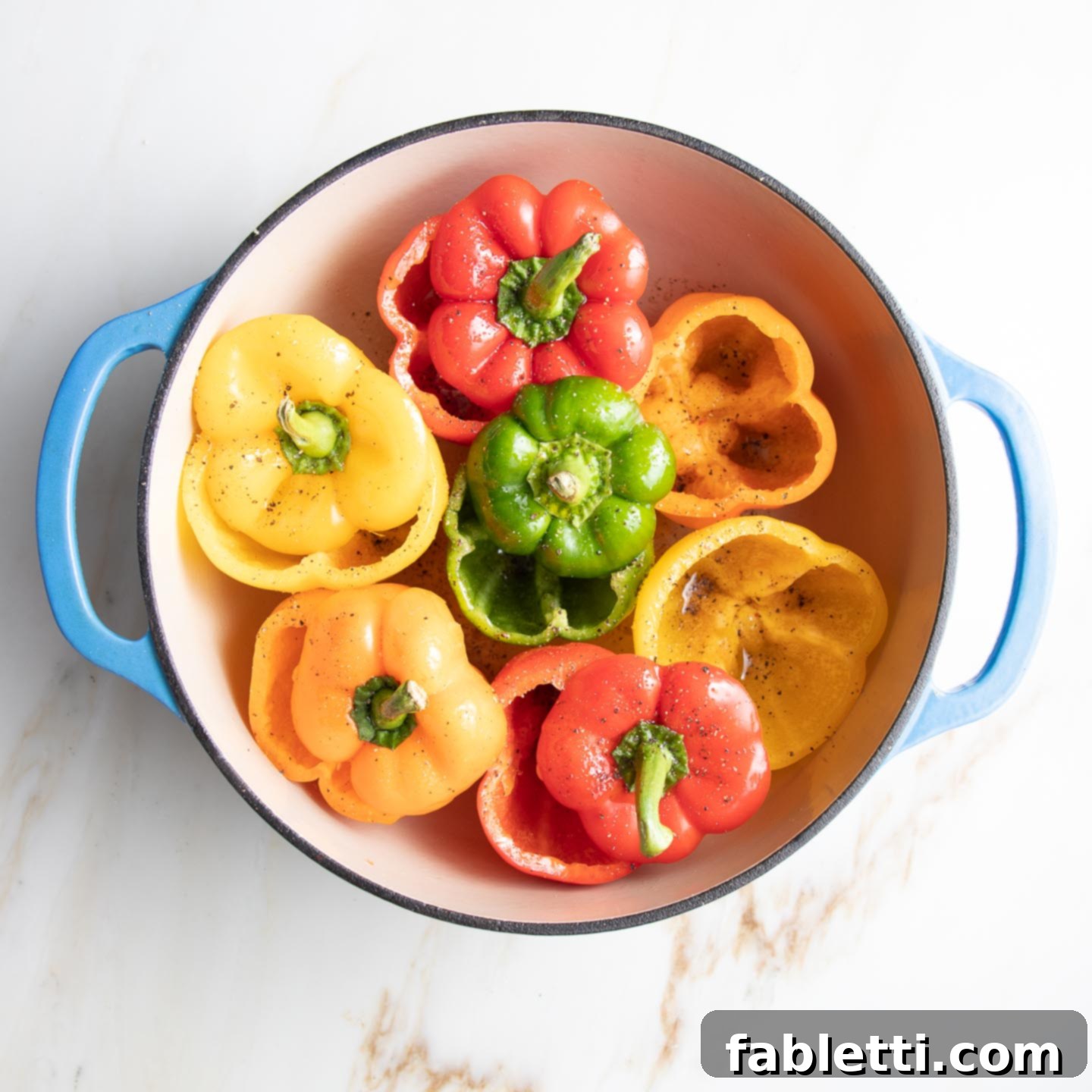 Hearty Vegan Lentil Stuffed Peppers 7 Red, orange, yellow, and green bell peppers, with their tops cut off, arranged tightly in a Dutch oven to stand upright.
