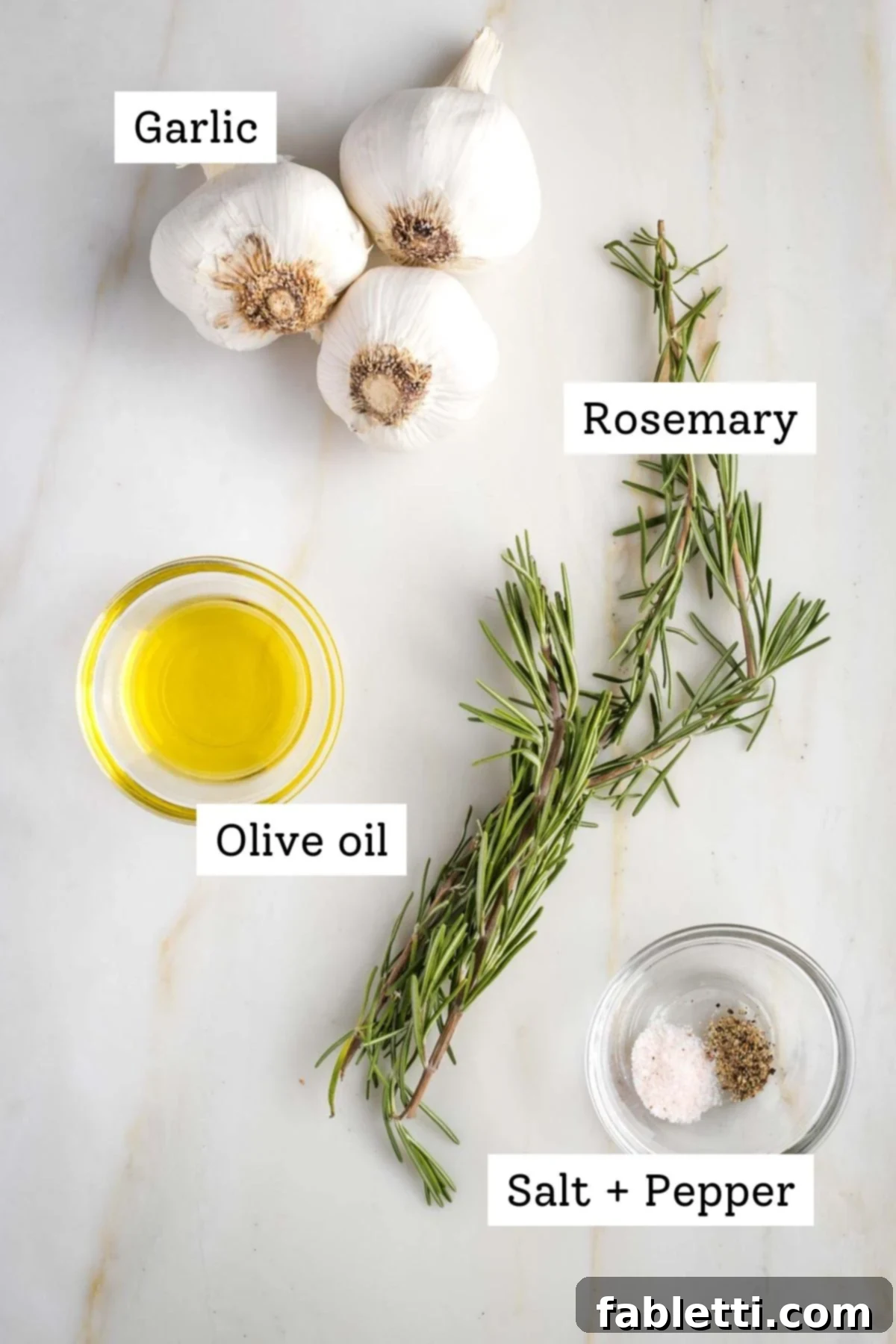 Sweet Creamy Oven Roasted Garlic 3 A collection of ingredients for roasted garlic: whole garlic heads, fresh rosemary, a bottle of olive oil, and small bowls of salt and pepper.