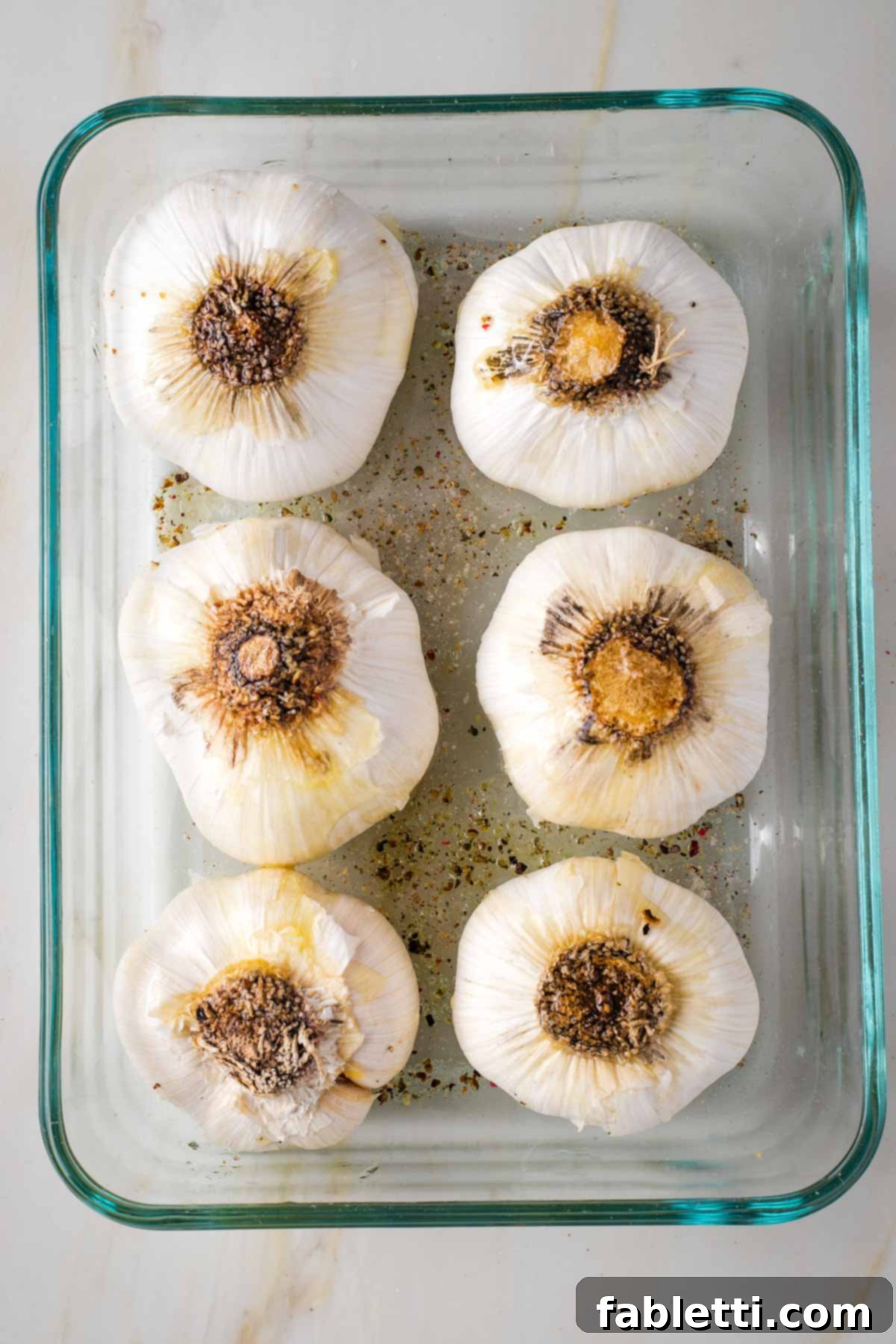 Sweet Creamy Oven Roasted Garlic 6 Six heads of garlic, now flipped root side up, resting in a small baking dish.