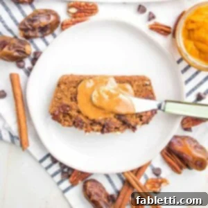 Harvest Spice Vegan Banana Loaf 12 Slice of pumpkin bread with a dollop of almond butter on a white plate. There are dates, cinnamon sticks, pecans and chocolate chips strewn around the sides of the plate.