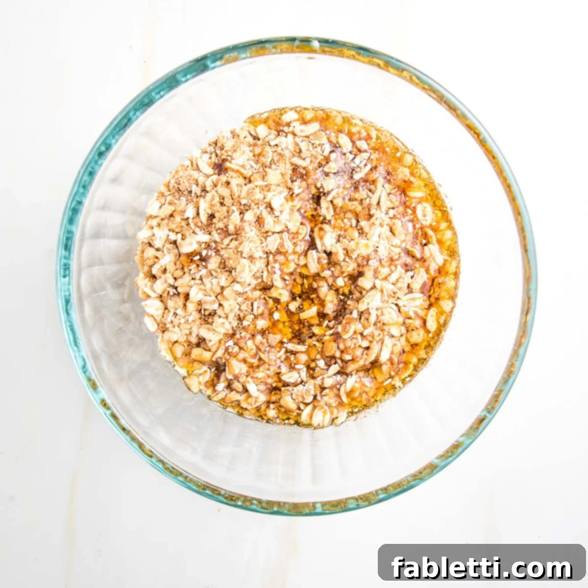 Naturally Sweet Dairy-Free Baked Apples 12 Golden pure maple syrup is gently poured into the bowl containing the ground oat and nut mixture, preparing the moist and cohesive filling for the baked apples.