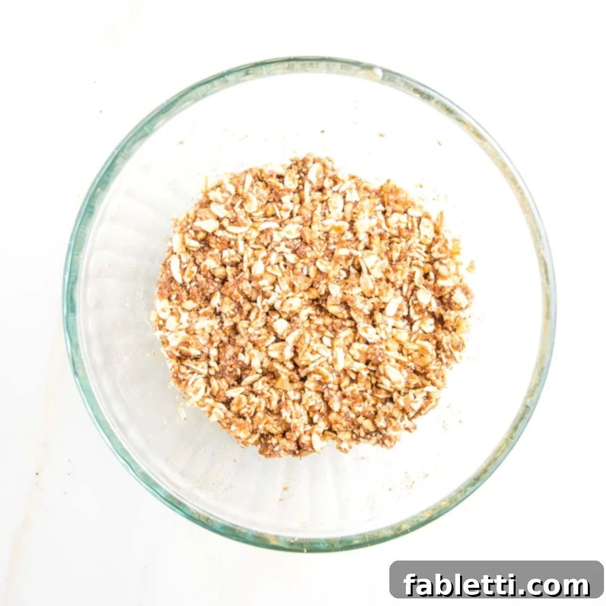 Naturally Sweet Dairy-Free Baked Apples 13 The fully mixed oat filling for baked apples in a medium-sized bowl, moist and cohesive, perfectly ready to be spooned into the cored fruit cavities.