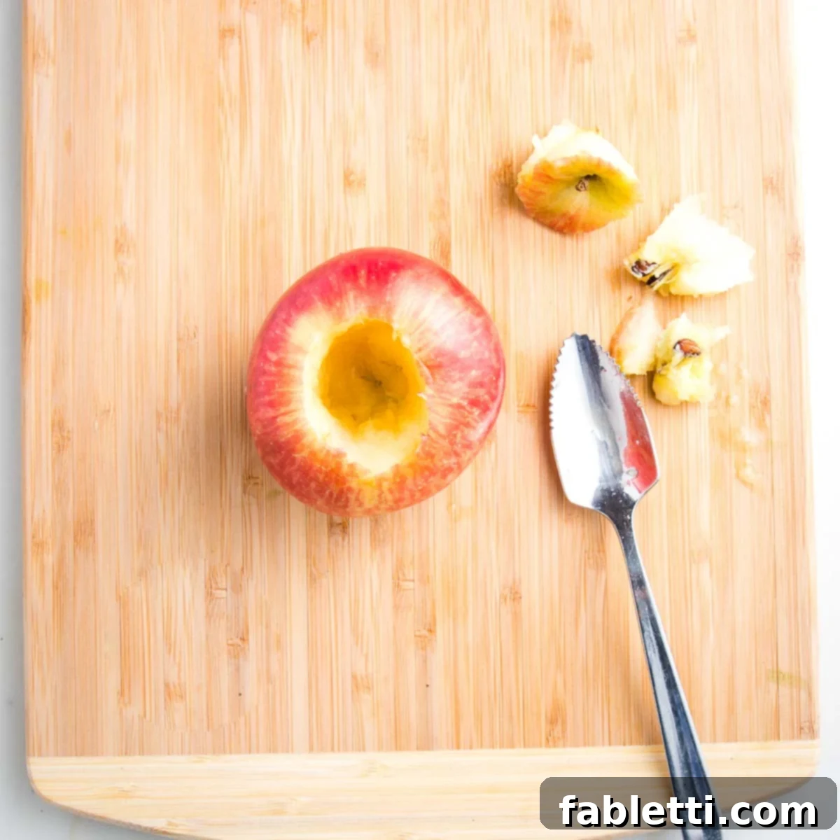 Naturally Sweet Dairy-Free Baked Apples 9 A cored apple achieved efficiently using a grapefruit spoon, showing a clean, hollow space ready for filling.
