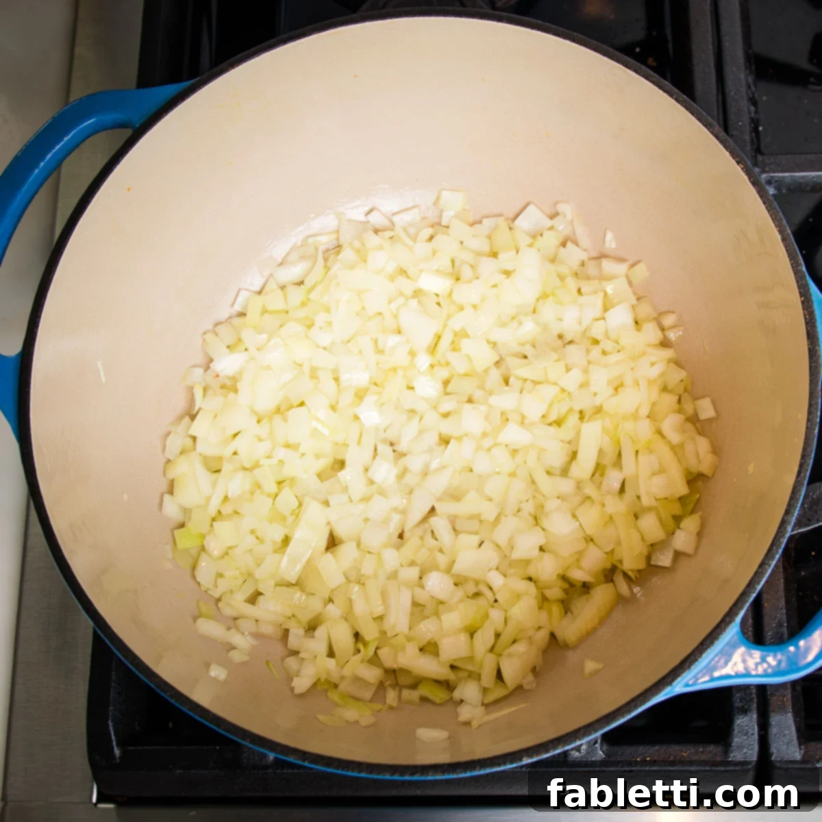 Diced onions gently cooking inside a sturdy Dutch oven, slowly turning translucent and fragrant.