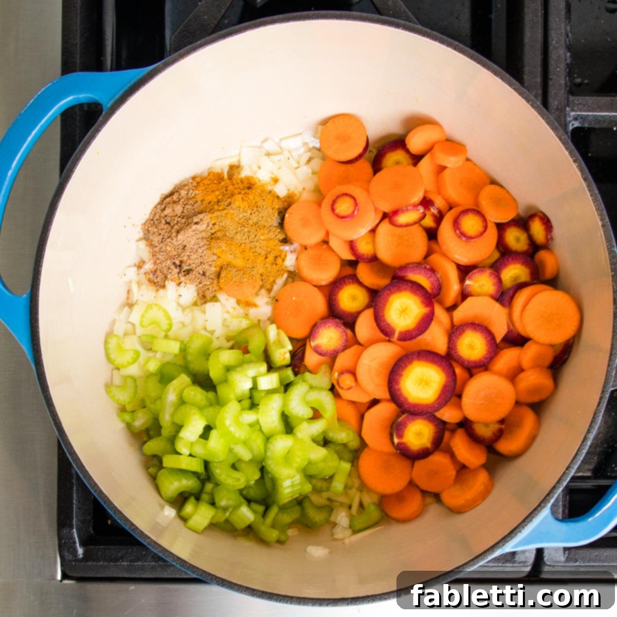 A Dutch oven now holds layers of colorful vegetables cooking, including vibrant purple and orange sliced carrots, crisp sliced celery, translucent onions, and a medley of fragrant spices.