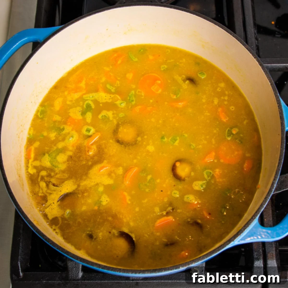 A harmonious mix of vegetables and broth are actively cooking in a Dutch oven, bubbling gently as the flavors meld.
