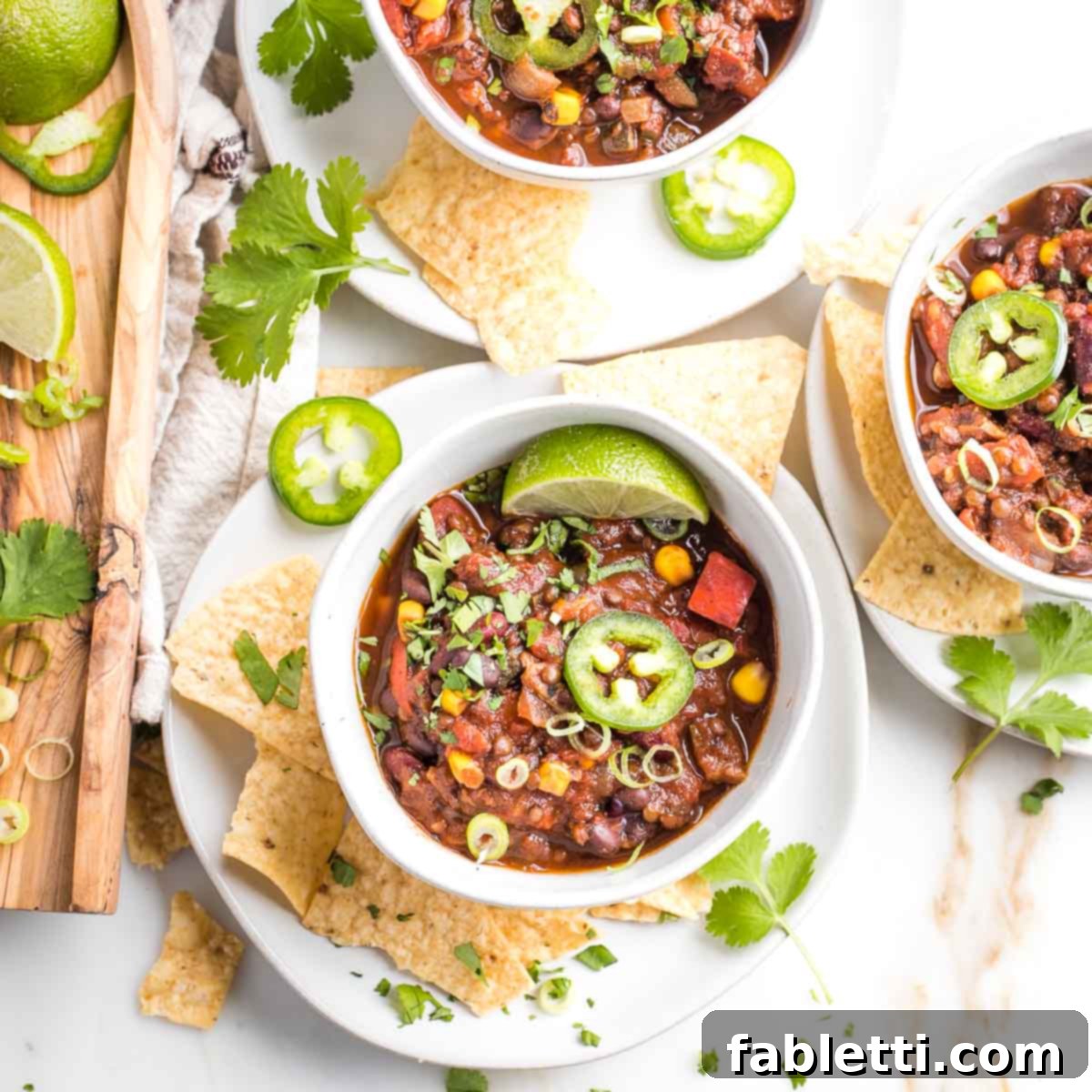 Quick and Flavorful Vegan Lentil Chili 11 A delightful array of vegan chili toppings laid out: bright lime wedges, fiery sliced jalapeños, aromatic fresh cilantro, and a pile of crunchy corn chips.