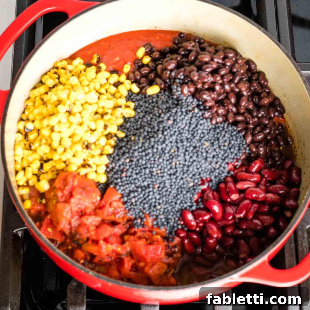 Quick and Flavorful Vegan Lentil Chili 8 A Dutch oven containing all the chili ingredients: canned diced tomatoes, black beans, kidney beans, frozen corn, and dried black beluga lentils, ready to be simmered.