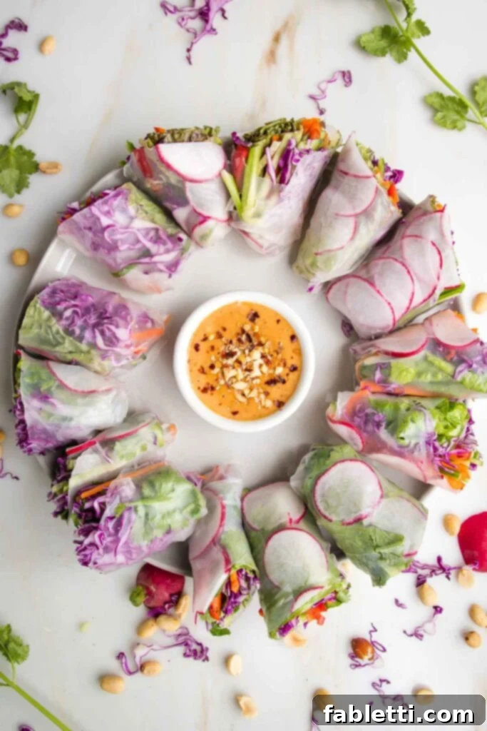 Circular arrangement of colorful fresh spring rolls with a small dish of creamy peanut sauce in the center.