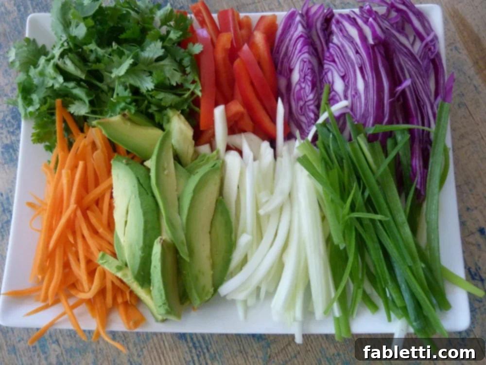 A tray overflowing with a vibrant assortment of perfectly julienned vegetables, meticulously prepared and ready to be wrapped into fresh spring rolls.