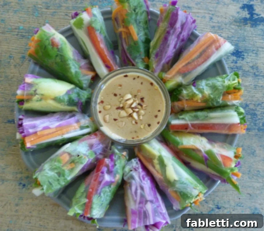 A vibrant platter of veggie spring rolls served alongside a bowl of rich peanut dipping sauce, showcasing the freshness and deliciousness of the homemade appetizer.